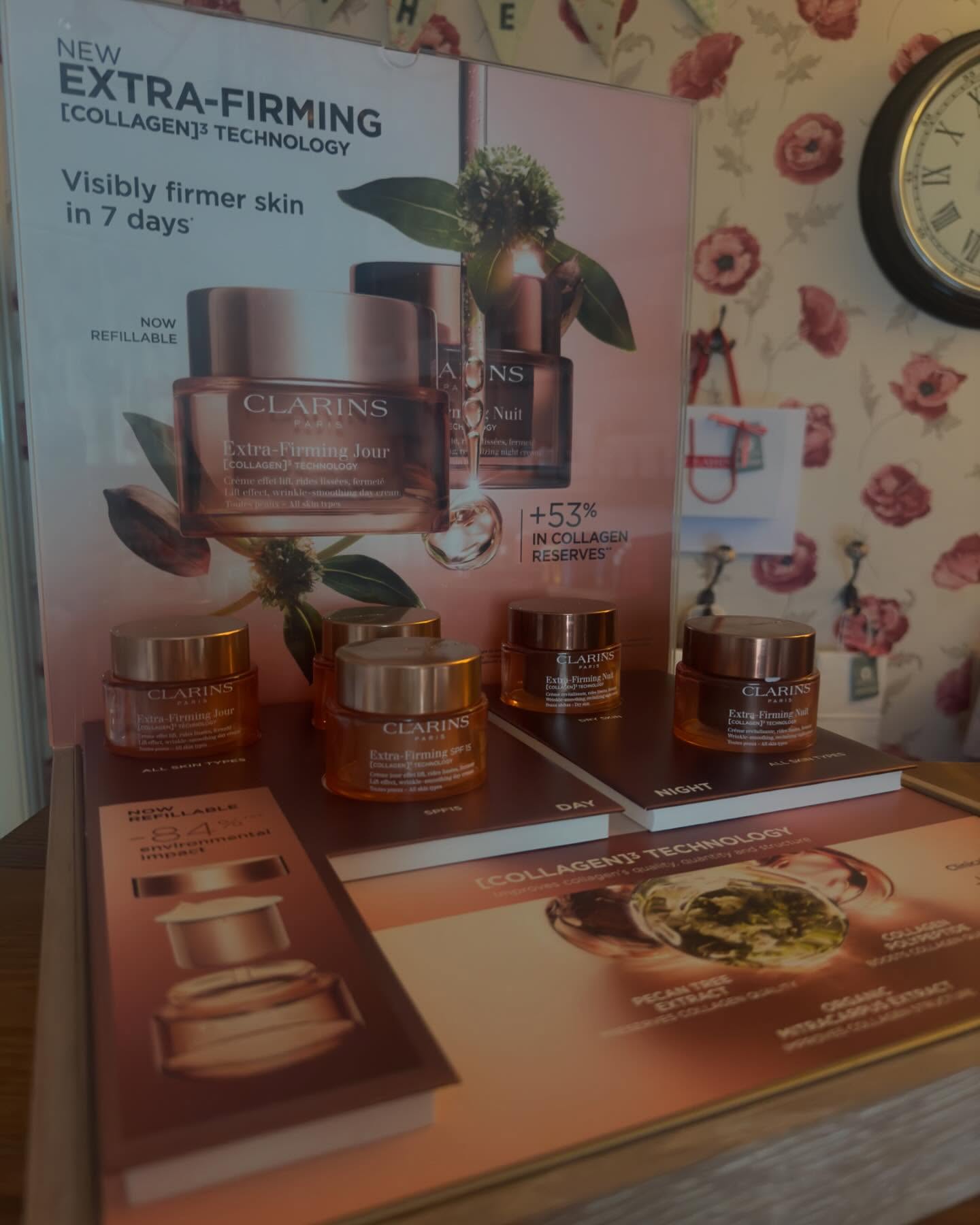 Clarins Extra-Firming display in the salon, against the poppy wallpaper beside the wall clock